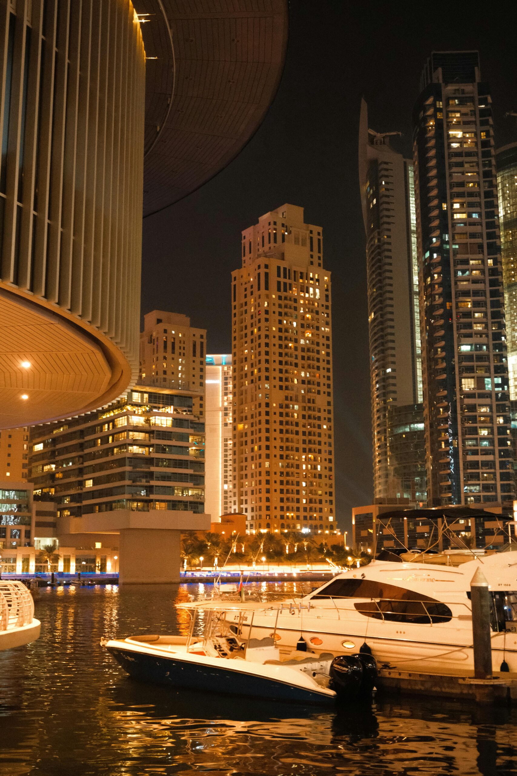 Captivating view of Dubai Marina at night with luxury yachts and stunning skyscrapers.