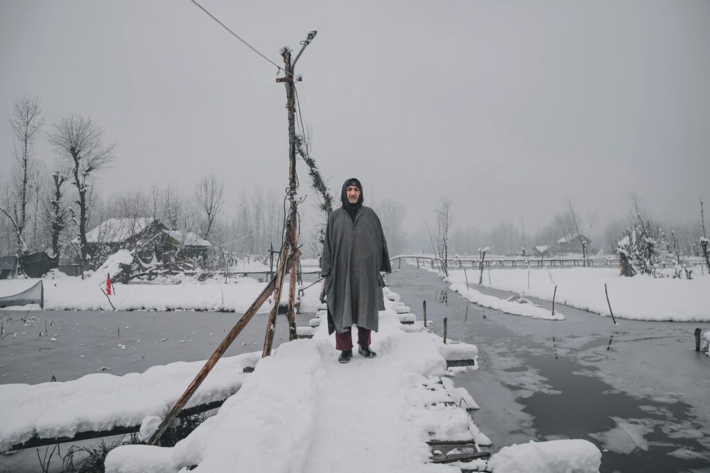 A serene winter scene in Jammu and Kashmir featuring fresh snowfall and traditional attire.