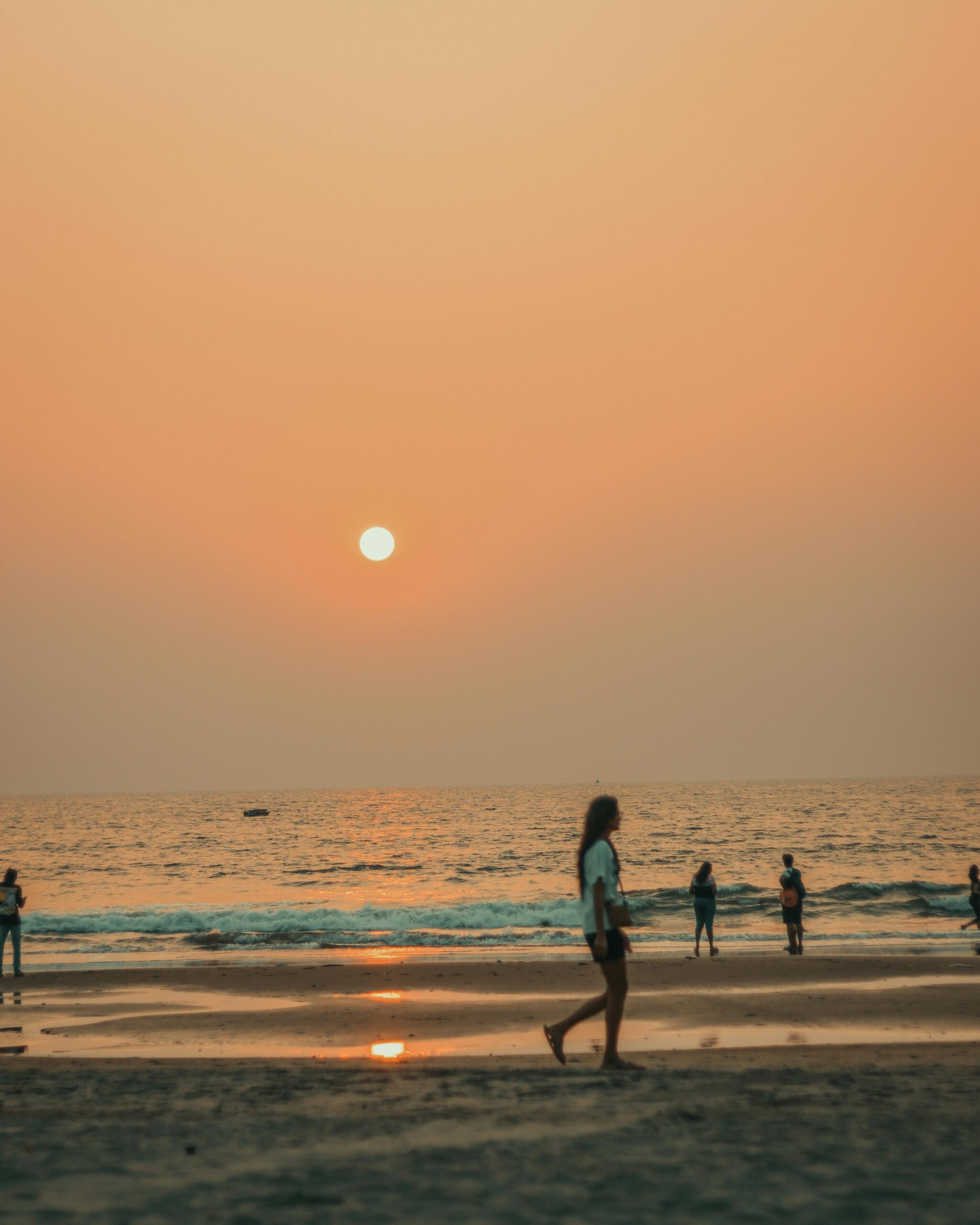 People enjoying a calm evening stroll along the beach at sunset.