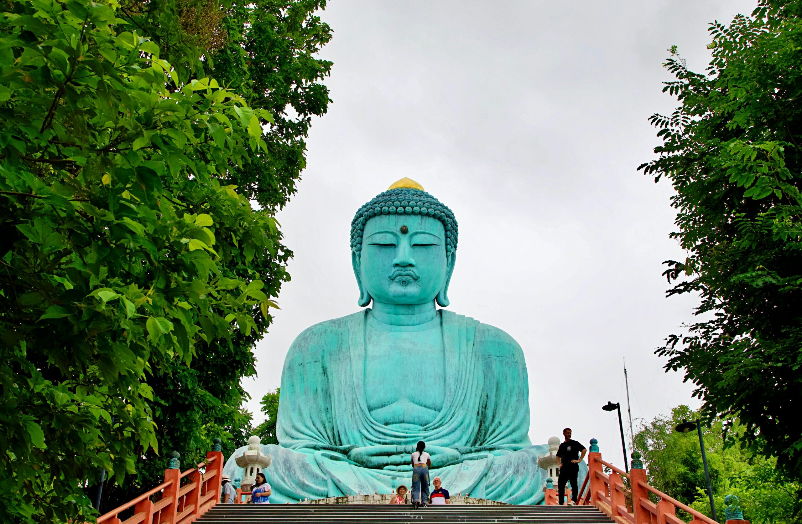 Impressive Giant Buddha statue in Thailand, framed by lush trees, showcasing serene beauty.