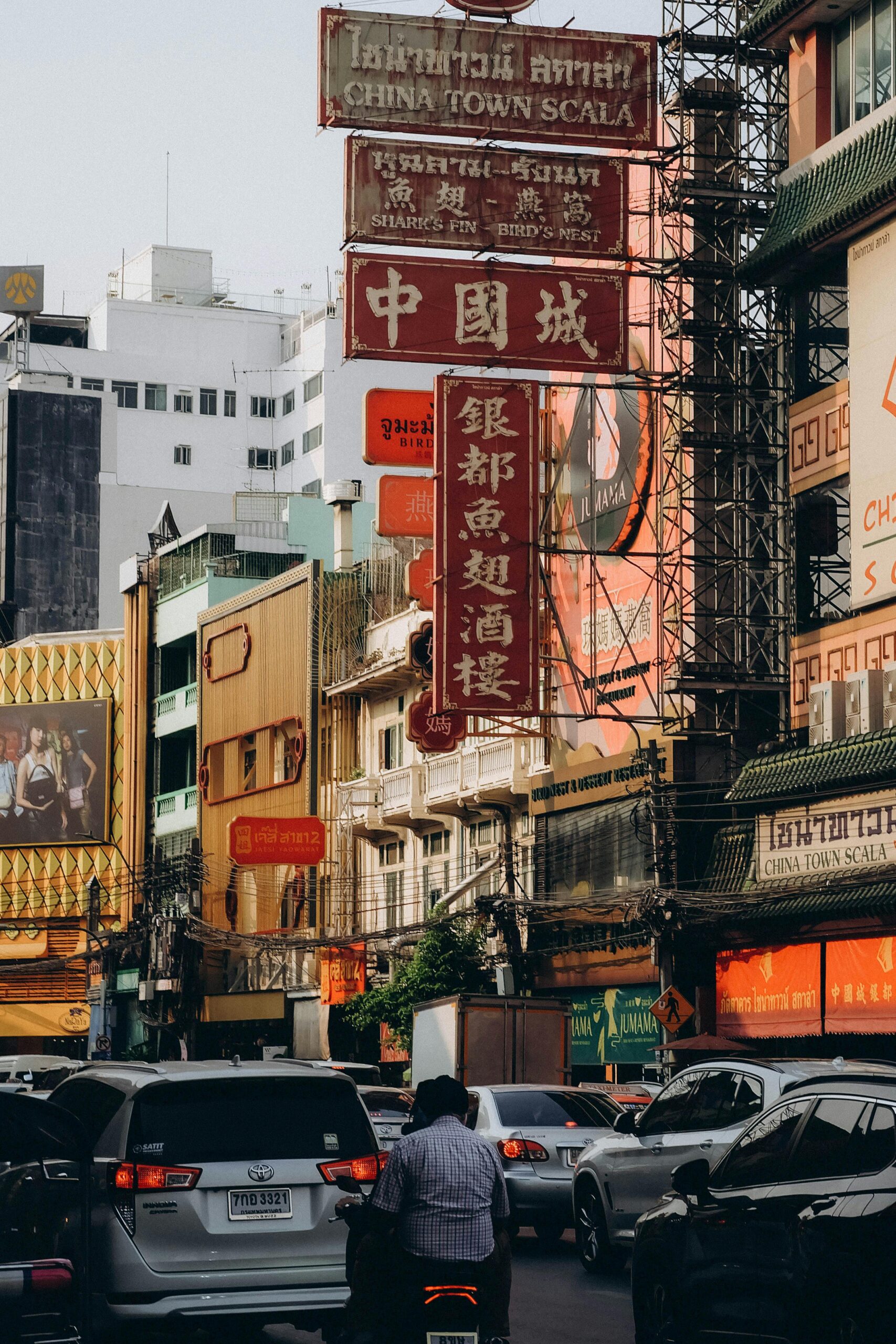 Bustling daytime scene in Bangkok's Chinatown with vibrant outdoor signs.